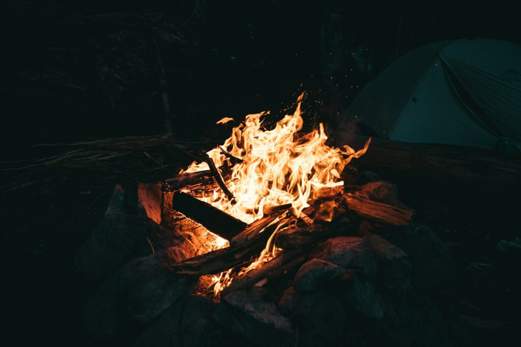 Campfire burning beside a tent at night